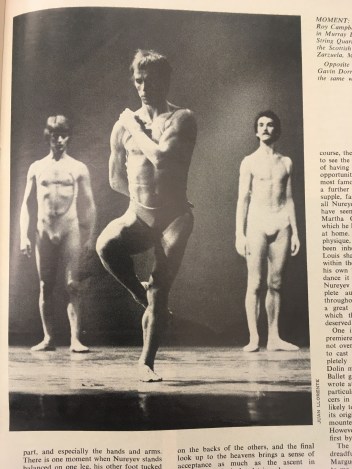 Black and white photograph of Rudolf Nureyev in the centre balancing on one leg and his left arm across his chest with Roy Campbell-Moore (left) and Brian Burn (right) behind him , all dressed in sleeveless leotards cut away at the front so their chests are bare