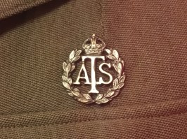 Badge with initials ATS with a crown over them and surrounded by a wreath of leaves