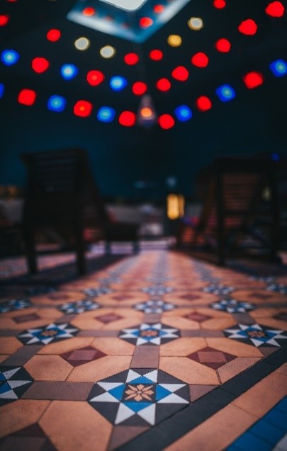 Turkish floor tiles in ochre, red, brown, white, blue arranged in a repeateding pattern of octagonals, triangles, squares and rectangles.